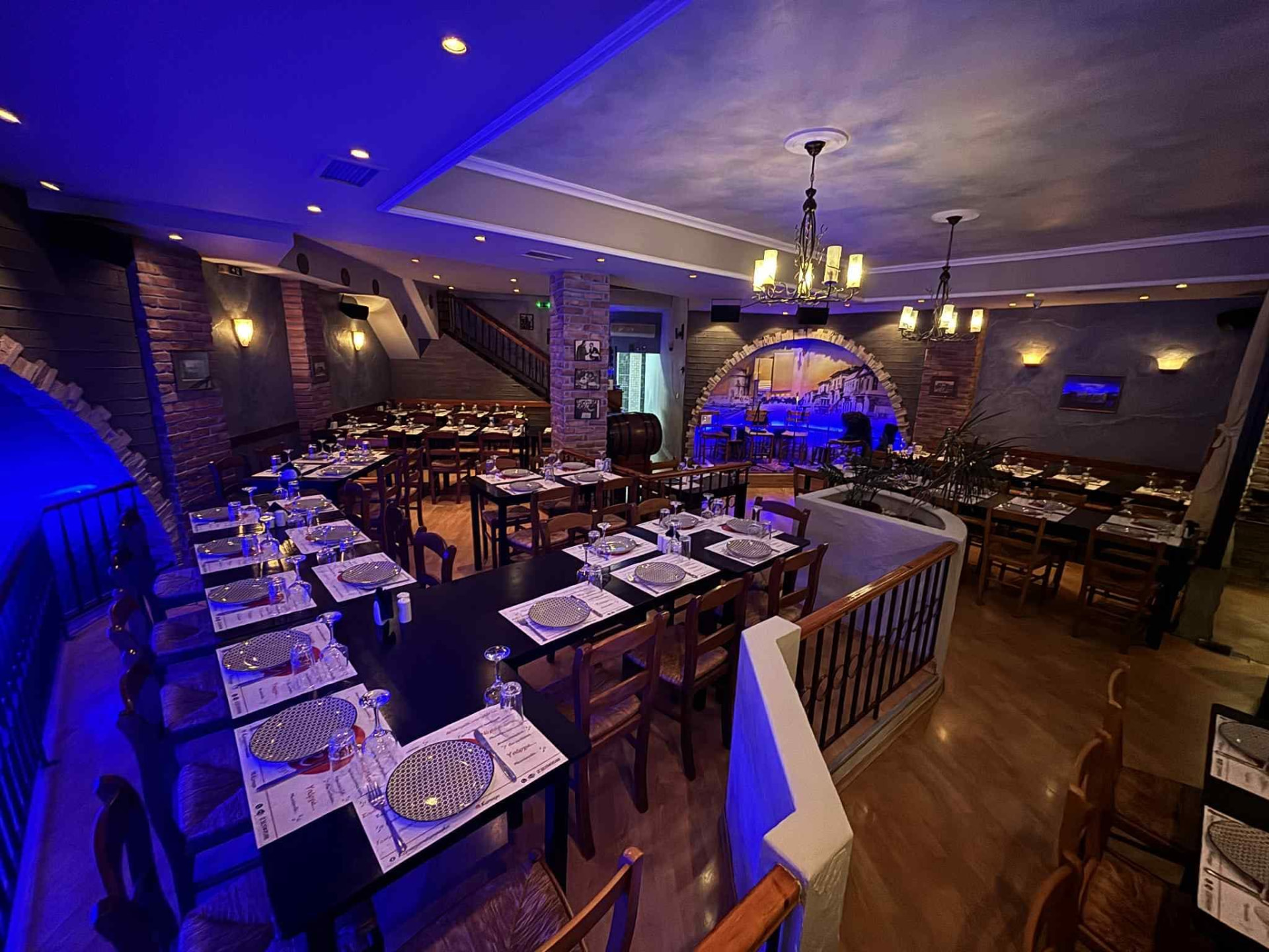 The dining room of Karnagio... meta mousikis in Kato Toumba, Thessaloniki, with laid tables and blue lighting